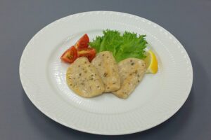皿に盛ったサーモンはんぺんの調理例。レタス、トマト、レモンを添えた写真。